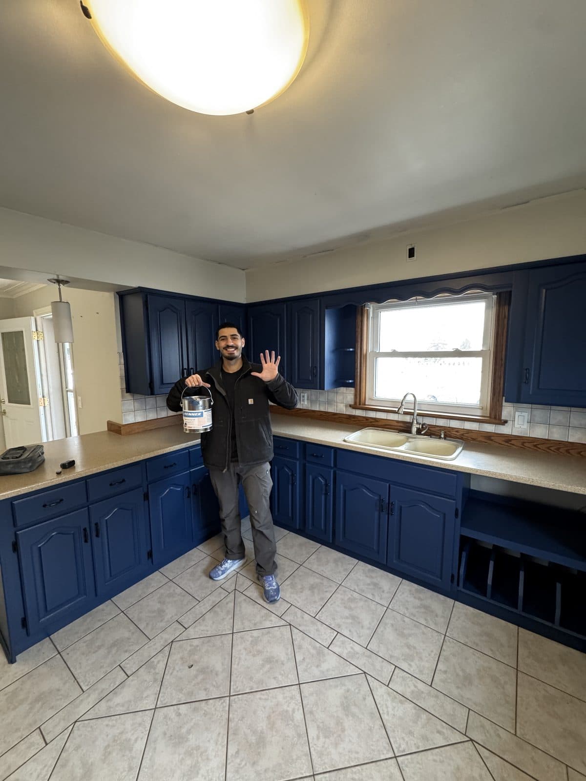 Navy blue cabinet refinish Primal Cabinet Painting owner standing in front of navy blue refinished kitchen cabinets