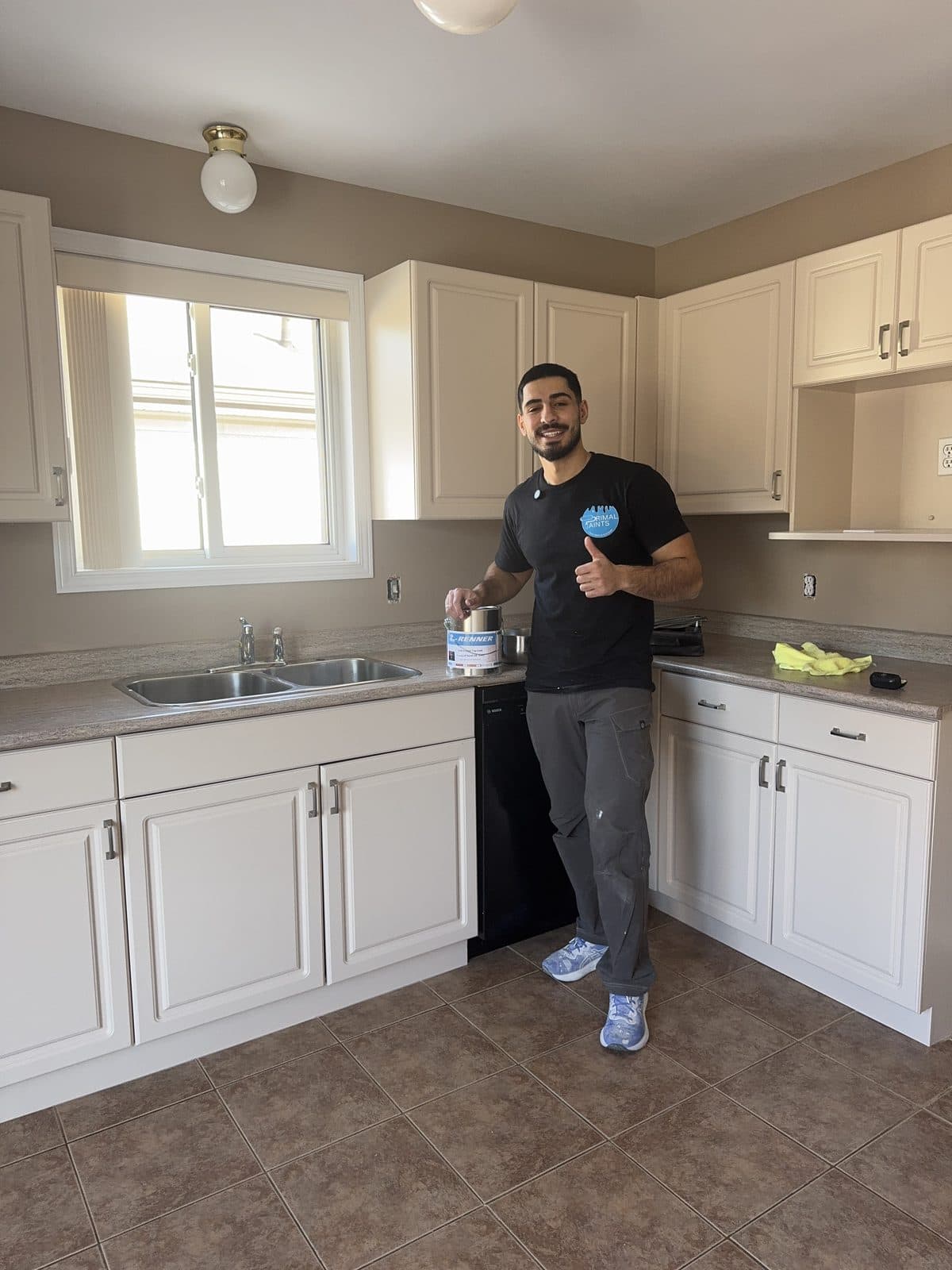 Small white kitchen cabinet refinish Small white kitchen cabinet refinishing project with owner holding a Renner can
