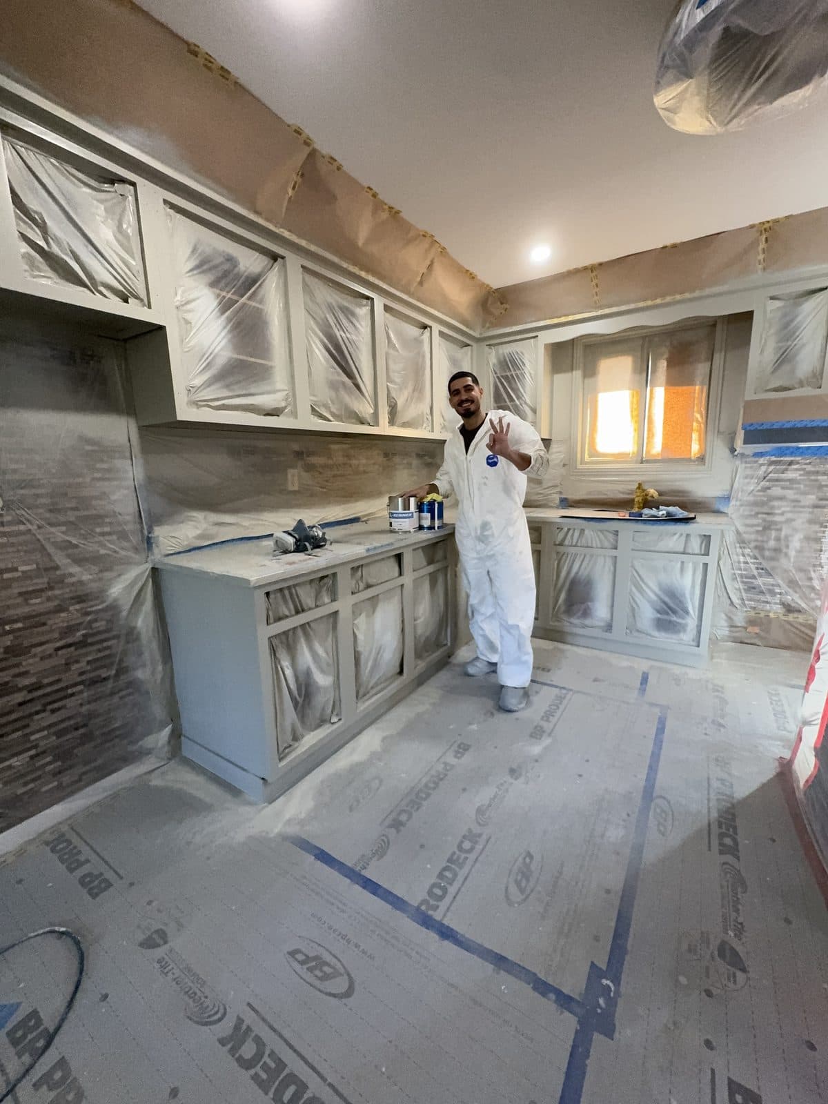 White kitchen masked for spray application White kitchen masked for spray application with owner holding paint
